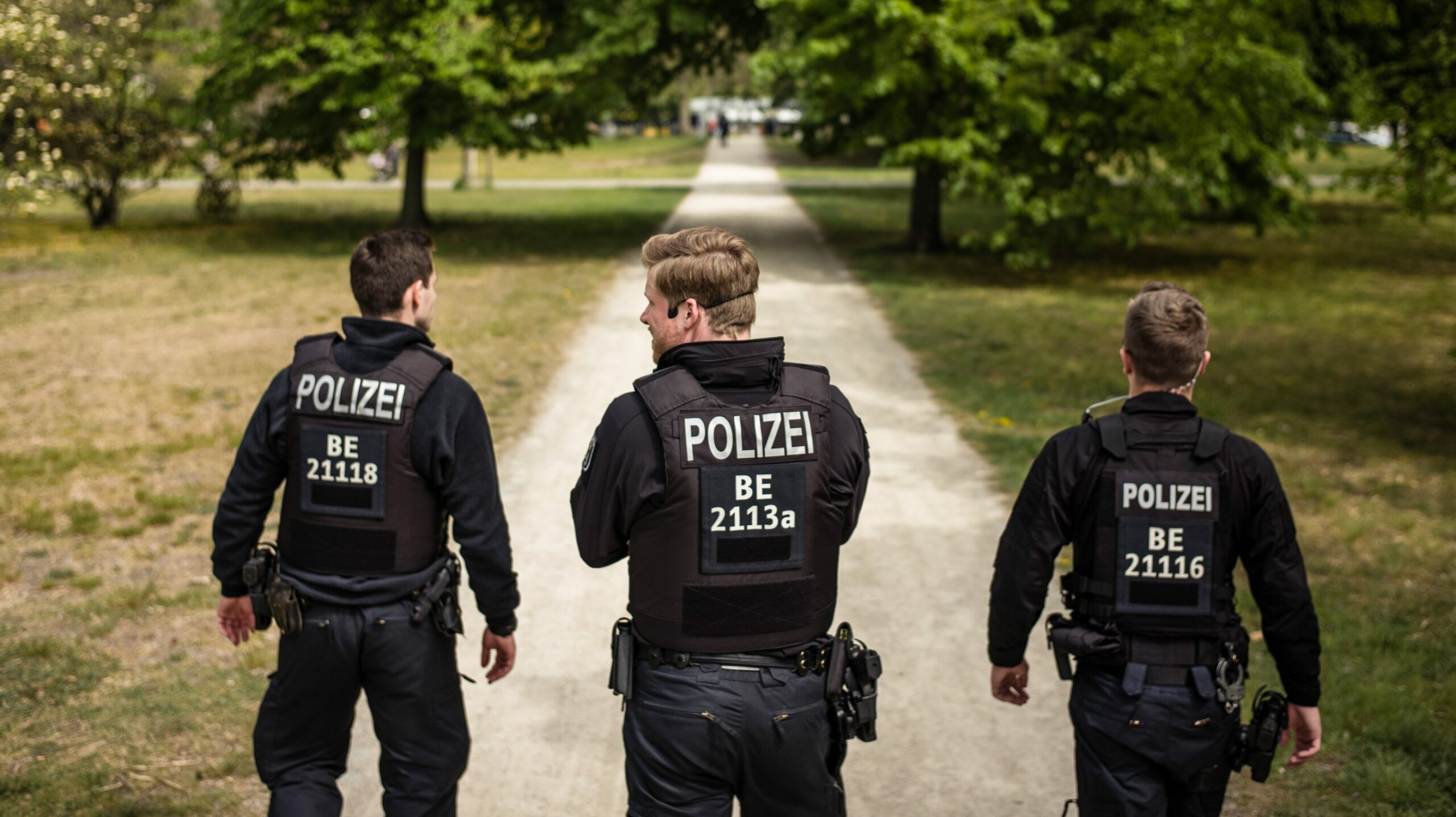 Drei Polizeibeamte laufen einen Parkweg hinunter